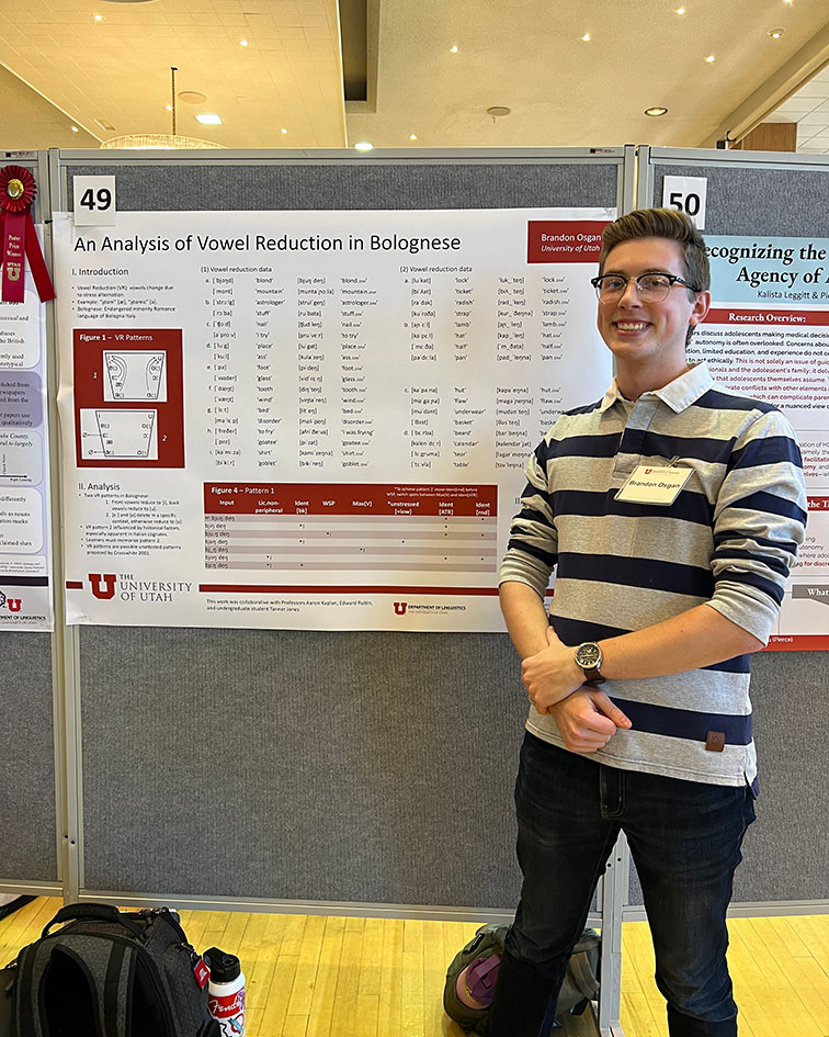 Brandon Osgan sitting in front of his research poster