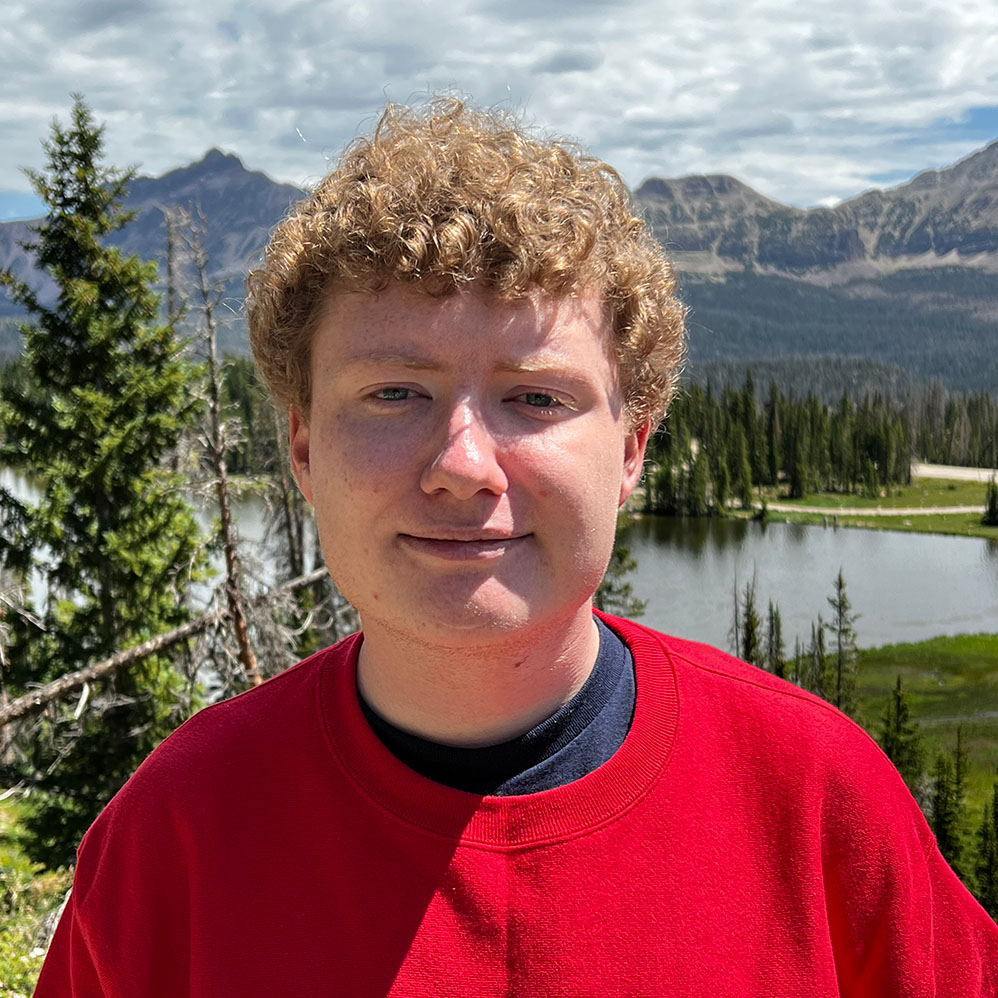 Zachery Theide in the mountains wearing a red sweatshirt