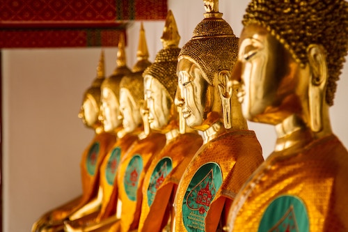 six golden buddhas lined up in a diagonal line