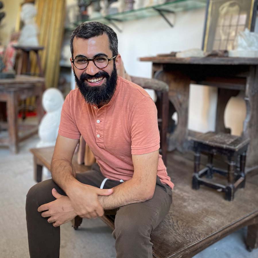 Navied Mahdavian sitting on a coffee table surrounded by artifacts