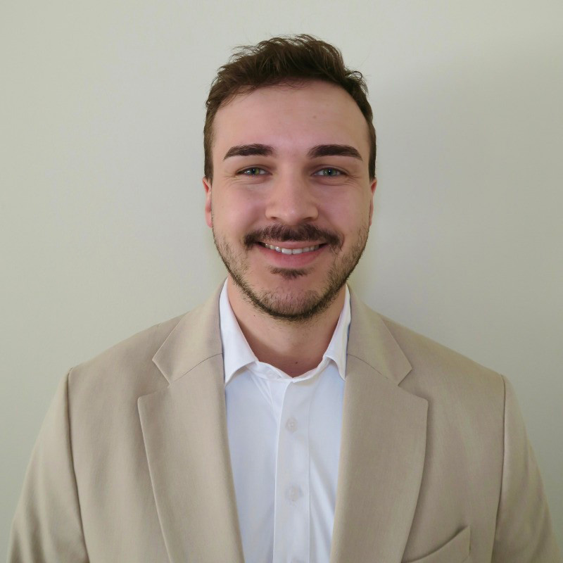 Casey wearing a tan blazer smiling at the camera