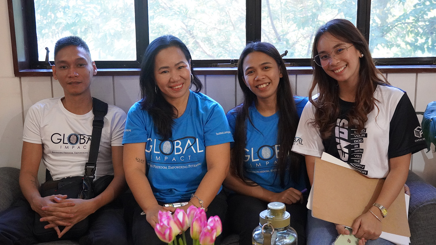 Four people in blue and white shirts from the Global Impact nonprofit team.