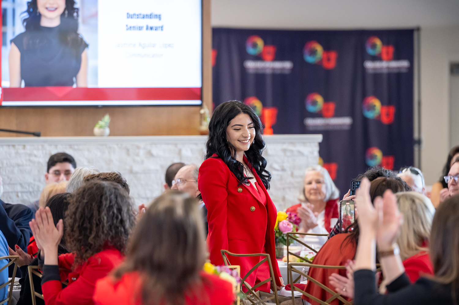Guests at the Distinguished Alumni Luncheon acknowledge student award winner Jasmine Aguilar Lopez