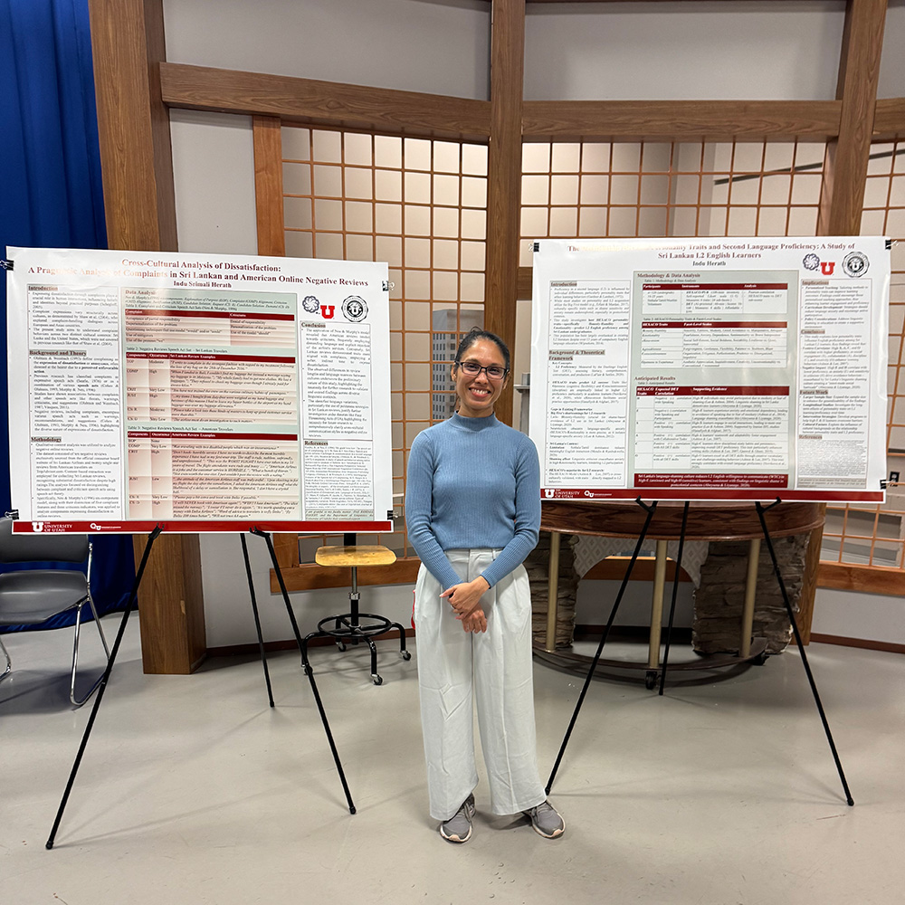 Indu stands in the middle with 2 large research posters on each side.