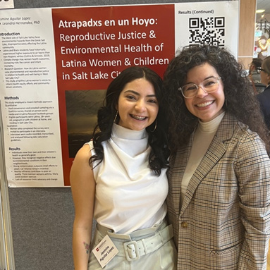 Jasmine and Leandra standing with their research poster in the back.