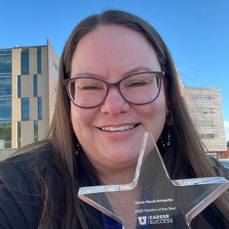 Karen holding her star-shaped award by her face and smiling at the camera