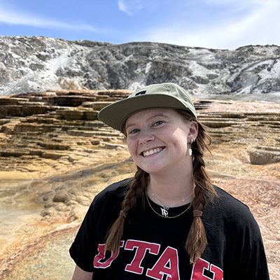 Olivia smiles at the camera, standing in front of an arid mountain scene