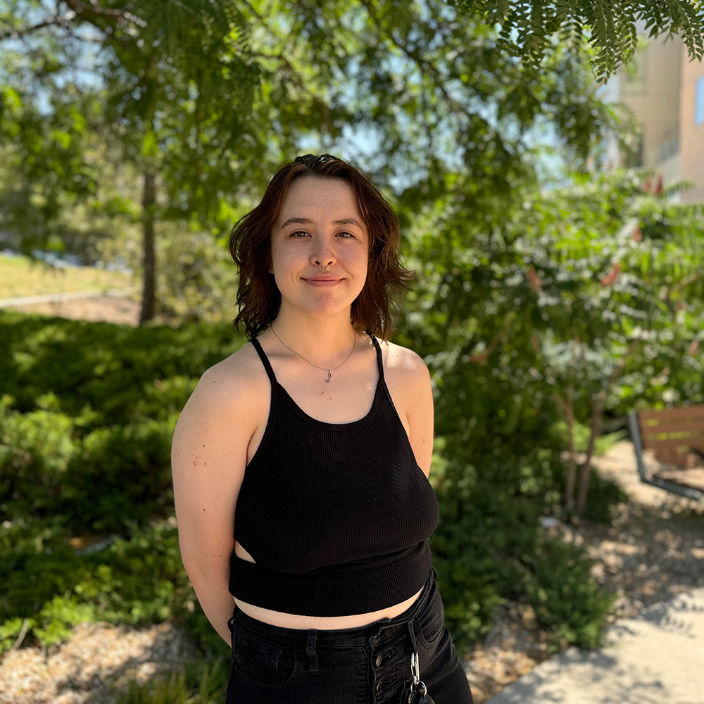 Pamalatera smiling at the camera in front of a large tree