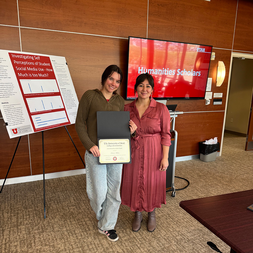 Lepa and Analise standing together and smiling at the camera. Analise is holding a certificate.