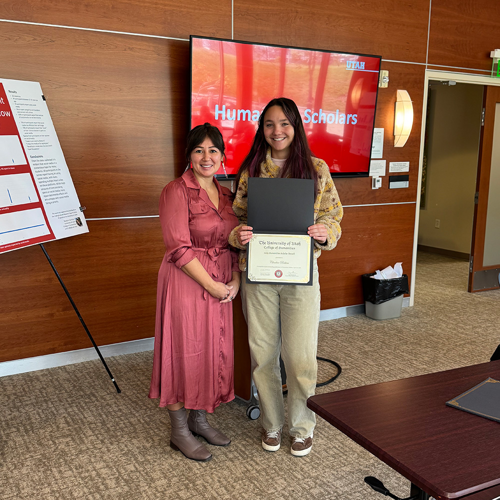 Lepa and Charlese standing together and smiling at the camera. Charlese is holding a certificate.