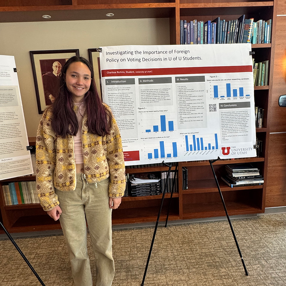 Charlese standing with her research poster on the right-side of her.