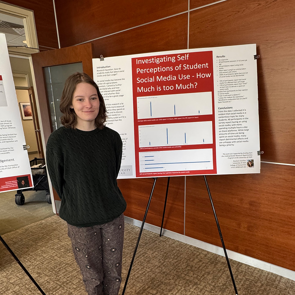 Rozz standing with her research poster on the right-side of her.