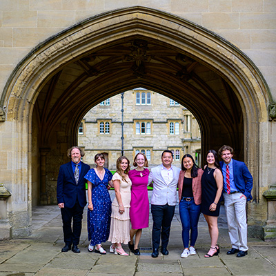 Adam (on the far right) is standing with other students in front on a large stone arch at Oxford University