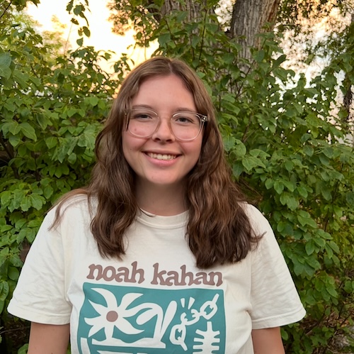 Alyssa Mott standing by a greenery and smiling at the camera