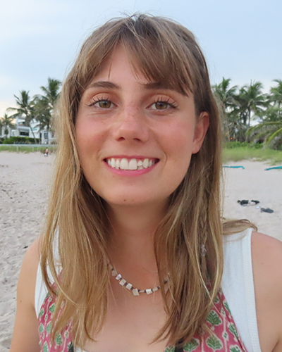 Ashlyn on a white sand beach smiling at the camera