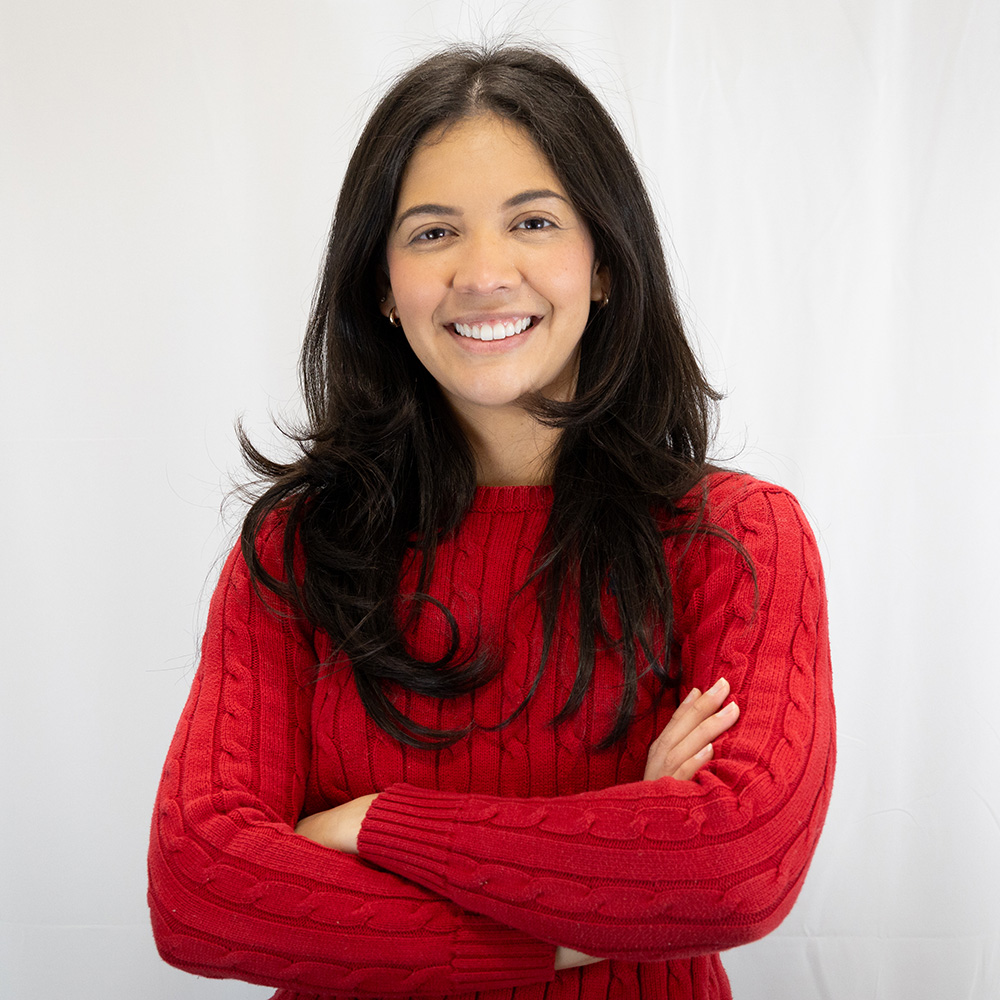 Daniela wearing a red sweater and smiling at the camera