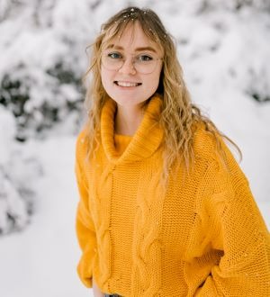 Maggie Bringhurst smiles at the camera, wearing a yellow sweater in the snow