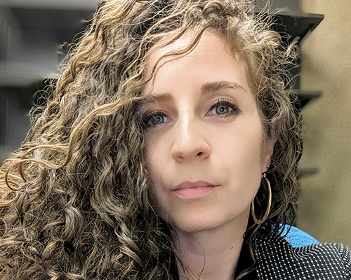 Close up of Annie with her curly hair pushed to the left and a stoic expression on her face.